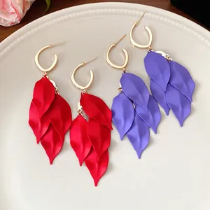 Detail of matte spray-painted leaf-shaped tassel earrings in red and purple