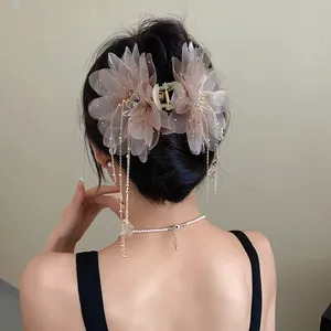 Back view of a gentle chiffon flower hair claw clip with tassels on model's hair