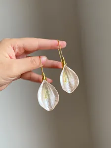 Close-up view of elegant petal drop earrings with pearlescent finish and gold hooks