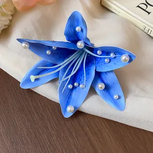 Vue détaillée d'une élégante pince à cheveux fleur de lys en tissu bleu avec perles blanches