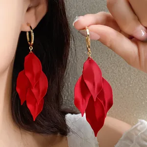Close-up of red matte leaf drop earrings with elegant gold hoops on an Asian model