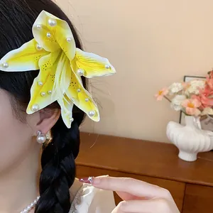 Détail rapproché d'une pince à cheveux en tissu lys jaune avec des accents de perles