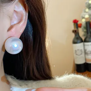 Primo piano di un grande orecchino a perla bianca minimalista sul lobo dell'orecchio
