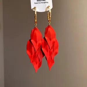 Close-up detail of vibrant red layered petal tassel earrings with elegant gold hoops