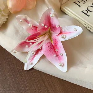 Détail d'une barrette à fleurs en tissu rose ornée de perles blanches sur fond doux et clair.