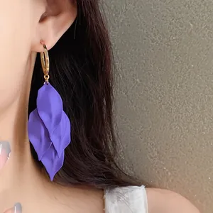 Detailed view of elegant purple petal tassel earrings worn by a model in a minimalist setting