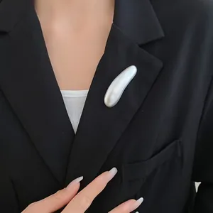 Primo piano di un'elegante spilla geometrica a goccia d'argento su un blazer nero