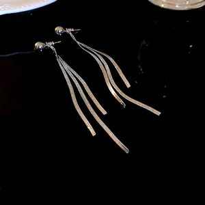 Dettaglio di lunghi orecchini a nappa d'argento con fili di catena metallica lucida.