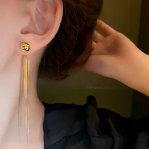 Dettaglio ravvicinato di eleganti orecchini a nappa d'oro lunghi indossati da una modella