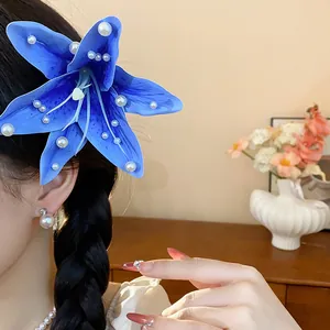 Gros plan d'une pince à cheveux lys en tissu bleu avec perles sur cheveux tressés