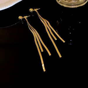 Eleganti orecchini lunghi a nappa d'oro con tripla catena a serpente su superficie nera