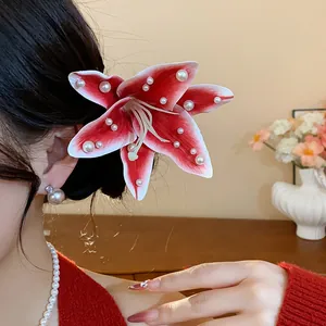 Détail d'une pince à cheveux fleur de lys en tissu rouge et blanc avec perles