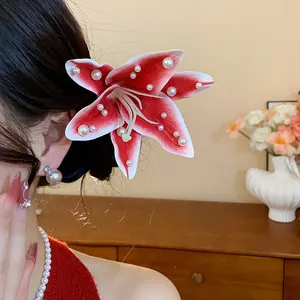Gros plan d'une élégante pince à cheveux fleur de lys rouge ornée de perles blanches