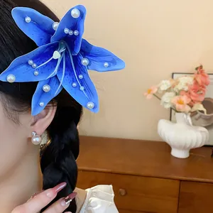 Vue détaillée d'une élégante pince à cheveux en lys bleu ornée de perles blanches brillantes.