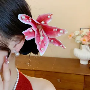 Vue détaillée d'une pince à cheveux fleur de lys en tissu rose avec perles blanches