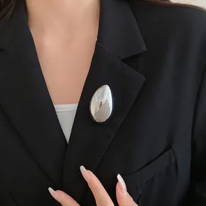 Primo piano di una spilla a goccia d'acqua in argento minimalista su un blazer nero elegante