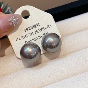 Primo piano di eleganti orecchini a perno grigi con perno in argento S925 su carta