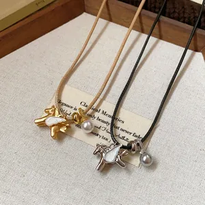 Vue détaillée de pendentifs cheval élégants avec perles et zircon sur colliers cordon.