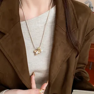 Gros plan du collier pendentif cheval doré avec perle sur une veste marron chic