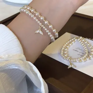 Elegant double-layered pearl bracelet featuring a sparkling zircon mermaid tail charm on wrist