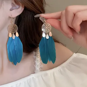 Elegant bohemian turquoise feather earrings with golden filigree, detail on a model.