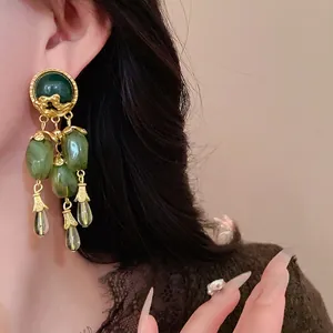 Orecchini vintage con nappe verde oliva e accenti dorati indossati da una modella.