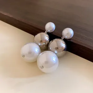 Detailed view of elegant silver needle earrings with large pearls and metallic spheres