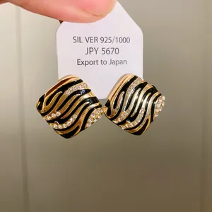 Macro view of gold zebra pattern earrings featuring inlaid rhinestones and silver pins