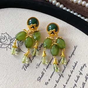 Dettaglio di orecchini vintage con nappe verde oliva e accenti metallici dorati