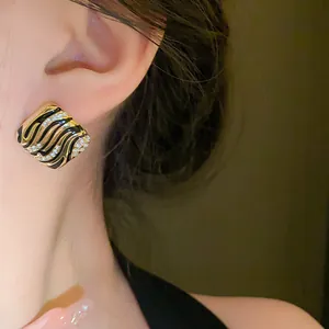 Detailed view of elegant square enamel earrings featuring rhinestones and a zebra wave pattern