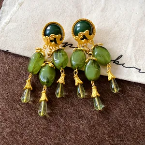 Dettaglio di orecchini vintage con nappe verde oliva e eleganti tocchi dorati.