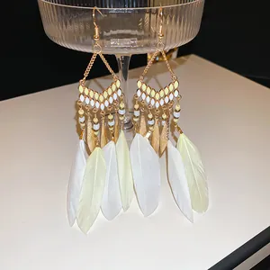 Bohemian ethnic style drop earrings featuring white feather tassels and gold beads