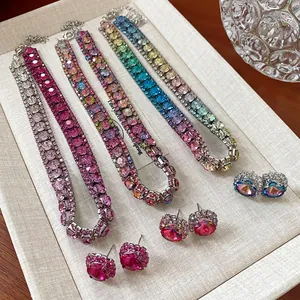 Dettaglio ravvicinato di collane girocollo con strass colorati e orecchini abbinati.