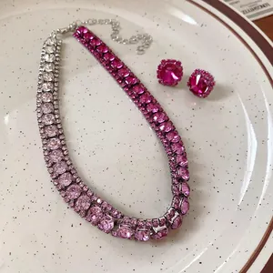 Primo piano di una collana girocollo con strass rosa e orecchini a bottone coordinati