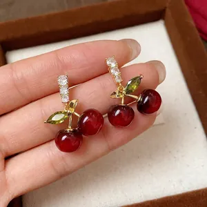 Elegant red resin cherry stud earrings featuring sparkling zircons and silver needles