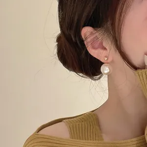 Elegante minimalistische vergoldete Perlenohrstecker, präsentiert von einem Model in sanftem Licht
