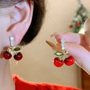 Detailed view of red resin cherry stud earrings featuring shiny zircon stones and silver needles