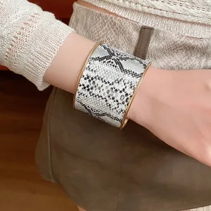 Breites Armband mit schwarz-weißem Schlangenmuster und eleganten goldfarbenen Rändern für Damen