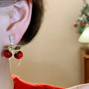 Close-up of sweet red resin cherry earrings with sparkling zircon leaves and studs.