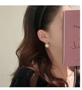 Elegante Doppelperlen-Ohrstecker am Ohr für eine detaillierte Nahaufnahme dargestellt