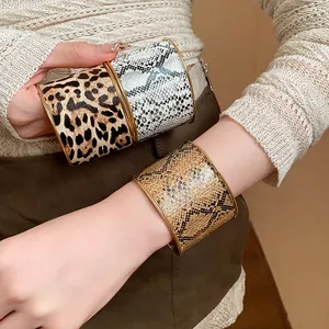 Nahaufnahme von breiten Armreifen mit Leoparden- und Schlangenmuster an einem Model