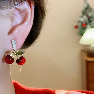 Close-up of sweet resin cherry earrings with sparkling zircon leaves and silver needles.