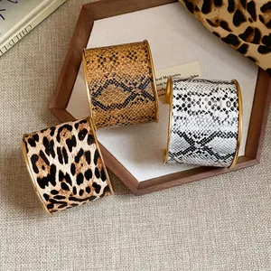 Nahaufnahme von breiten Manschettenarmbändern mit Leoparden- und Schlangenmuster