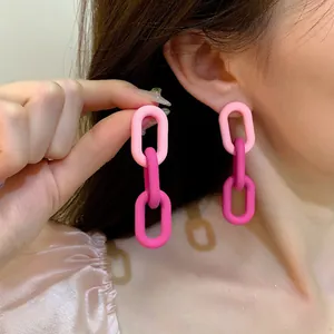 A detailed close-up of matte dopamine gradient pink chain-link earrings worn by a model