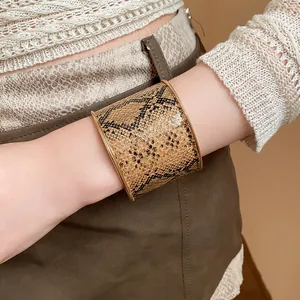 Nahaufnahme eines breiten Armreifs mit Schlangenmuster und goldenem Rand