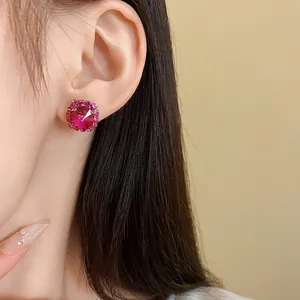 Primo piano di un elegante orecchino a bottone in cristallo magenta con bordo di strass