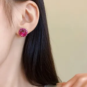 Primo piano di un orecchino a bottone con strass rosa indossato sull'orecchio di una modella