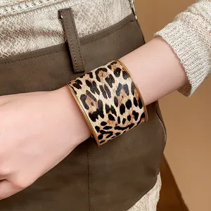 Detailansicht eines breiten Armreifs mit Leopardenmuster und goldfarbenem Metallrand.