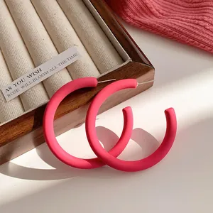 Vibrant dopamine pink matte hoop earrings featuring a minimalist C-shape design style
