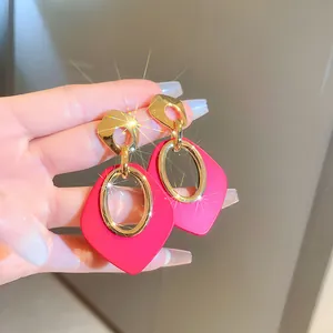 Detailed macro shot of stylish pink dopamine geometric drop earrings with gold accents